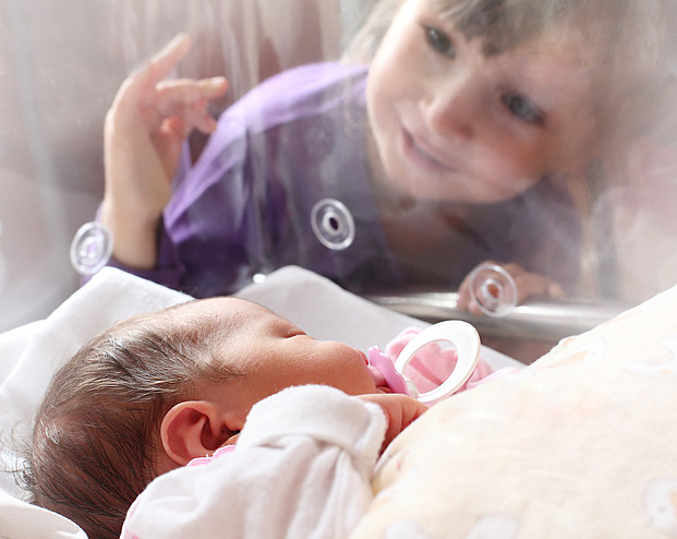 Mädchen vor Brutkasten der Schwester