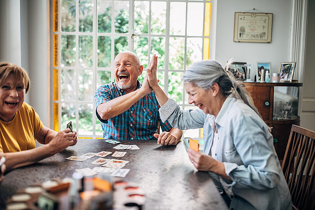 Senioren spielen gemeinsam Karten und sind sichtlich erfreut.